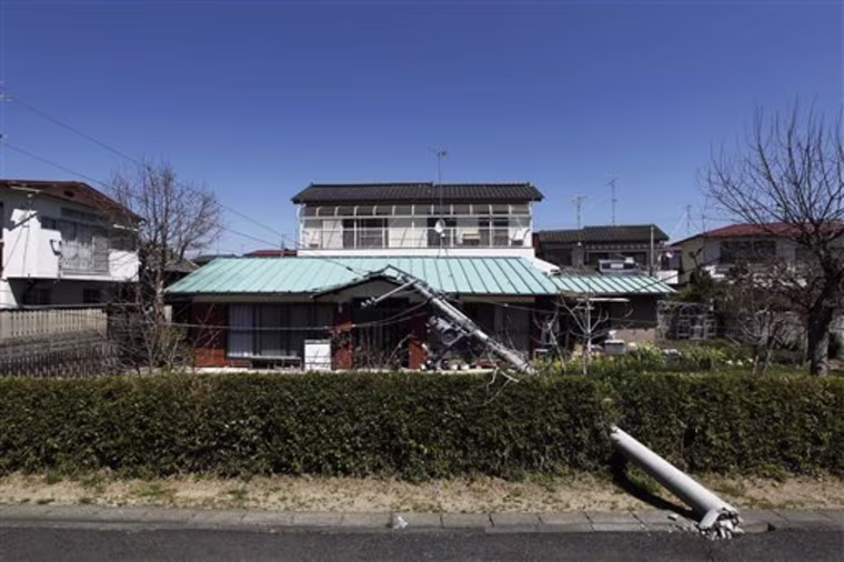 In this photo taken Sunday, April 17, 2011, a downed electrical pole lies on a house in Futaba, Fukushima Prefecture, northeastern Japan. Having survived the March 11, 2011 earthquake and tsunami, most of Futaba was intact, but thousands had to evacuate the city in the wake of the radiation warnings from the neighboring Fukushima Dai-ichi Nuclear power station. (AP Photo/Hiro Komae)